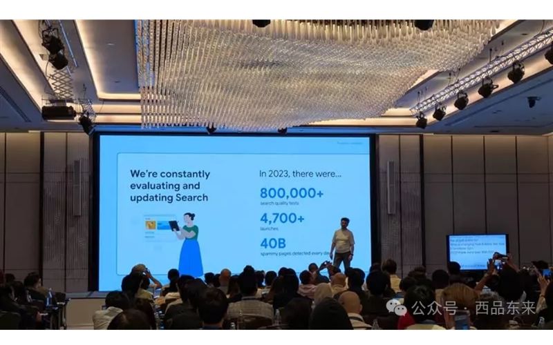 演讲厅内，屏幕上展示关于搜索更新的数据，观众正在观看。