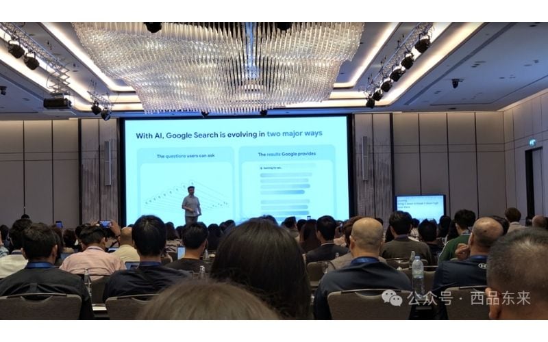 一位演讲者在会议室中上台演讲，背景是关于AI与谷歌搜索如何发展的幻灯片，观众坐在演讲者面前。