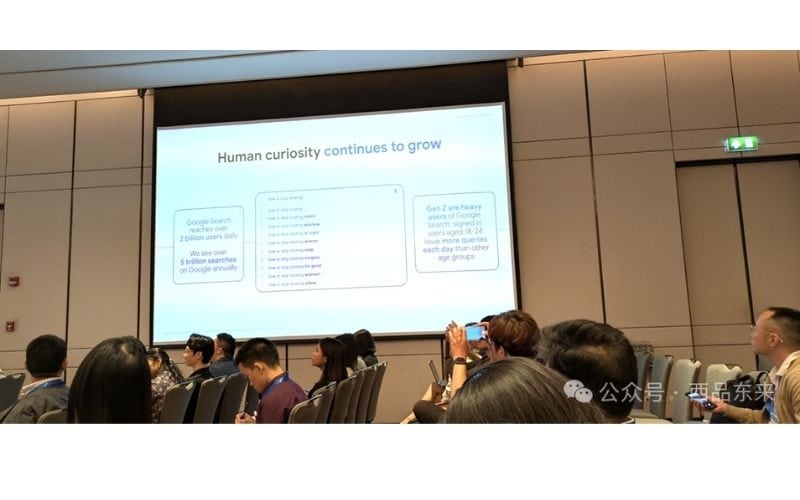 一群人坐在会议室中，看着显示屏上的演示文稿，屏幕上显示与Google搜索相关的统计数据。