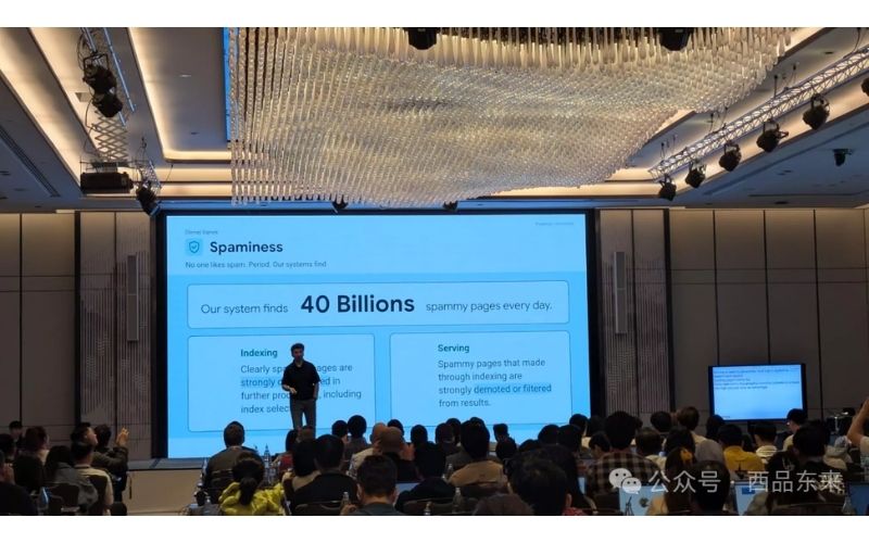 一名演讲者在会议上展示关于垃圾信息的幻灯片，幻灯片上显示系统每天检测到400亿个垃圾页面，观众在下面认真倾听。