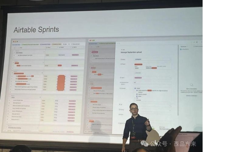 男子在台上演示 Airtable Sprints，投影屏幕上显示工作流程和任务面板。