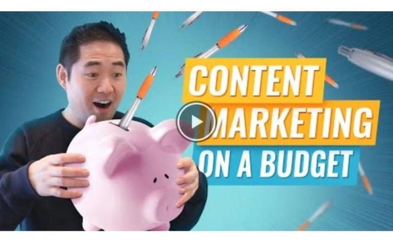 一名男子惊讶地看着一个存钱罐,上面有许多飞舞的笔,旁边有“CONTENT MARKETING ON A BUDGET”的文字。