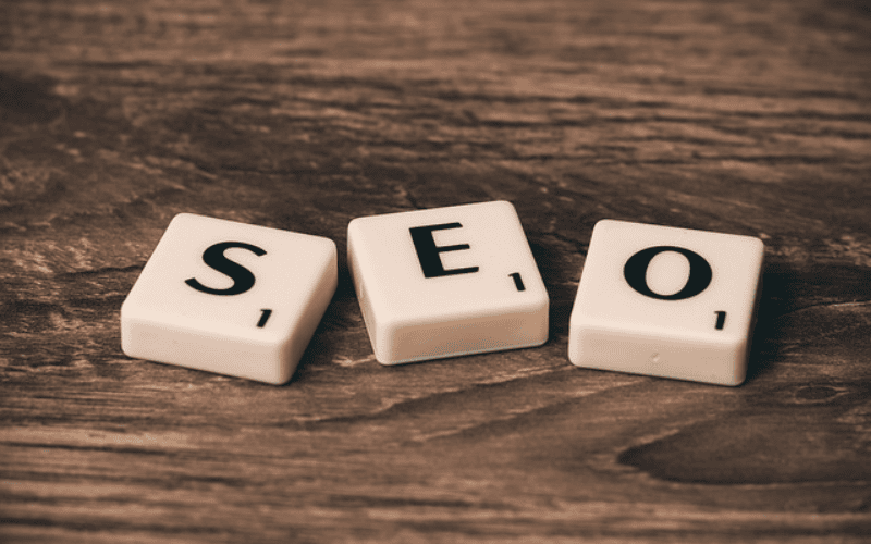 木质桌面上的拼字方块拼出 SEO,象征搜索引擎优化。